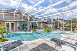 Gorgeous large tropical pool area with spa, surrounded by palm trees and shrubs.